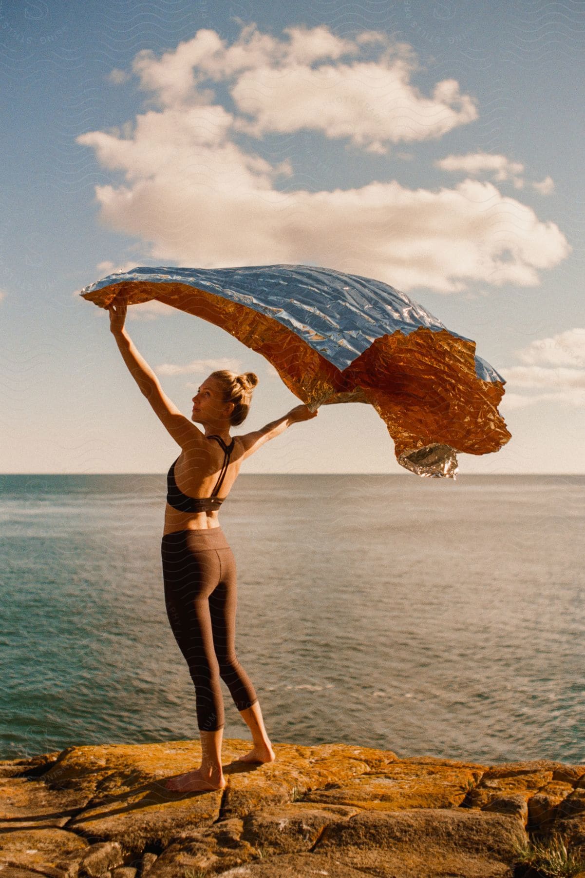 A young woman holding a flag on the shore of the sea.