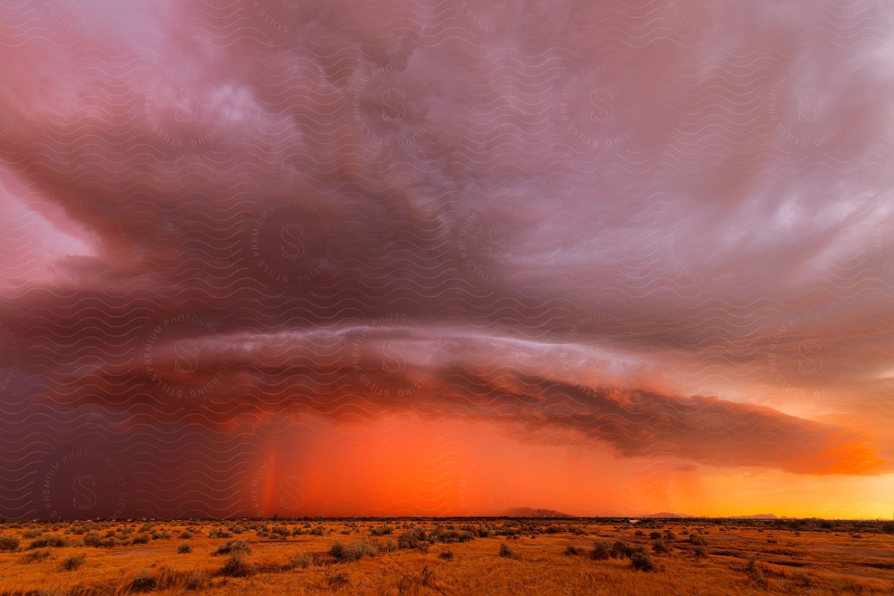 Dark storm clouds move over the desert under a colorful sunset sky