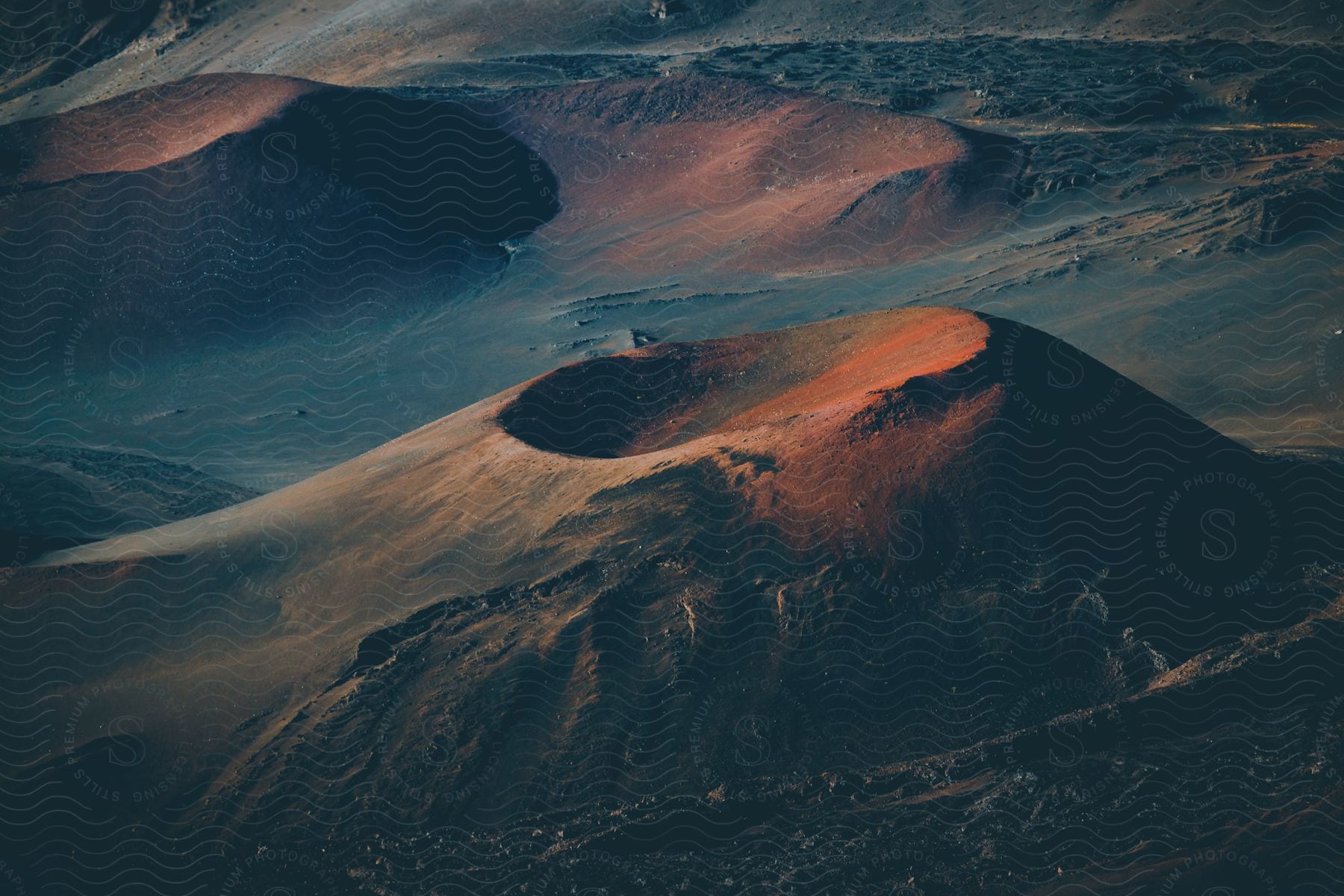 Large mountains with crater-like recesses at their top fill this arid landscape.