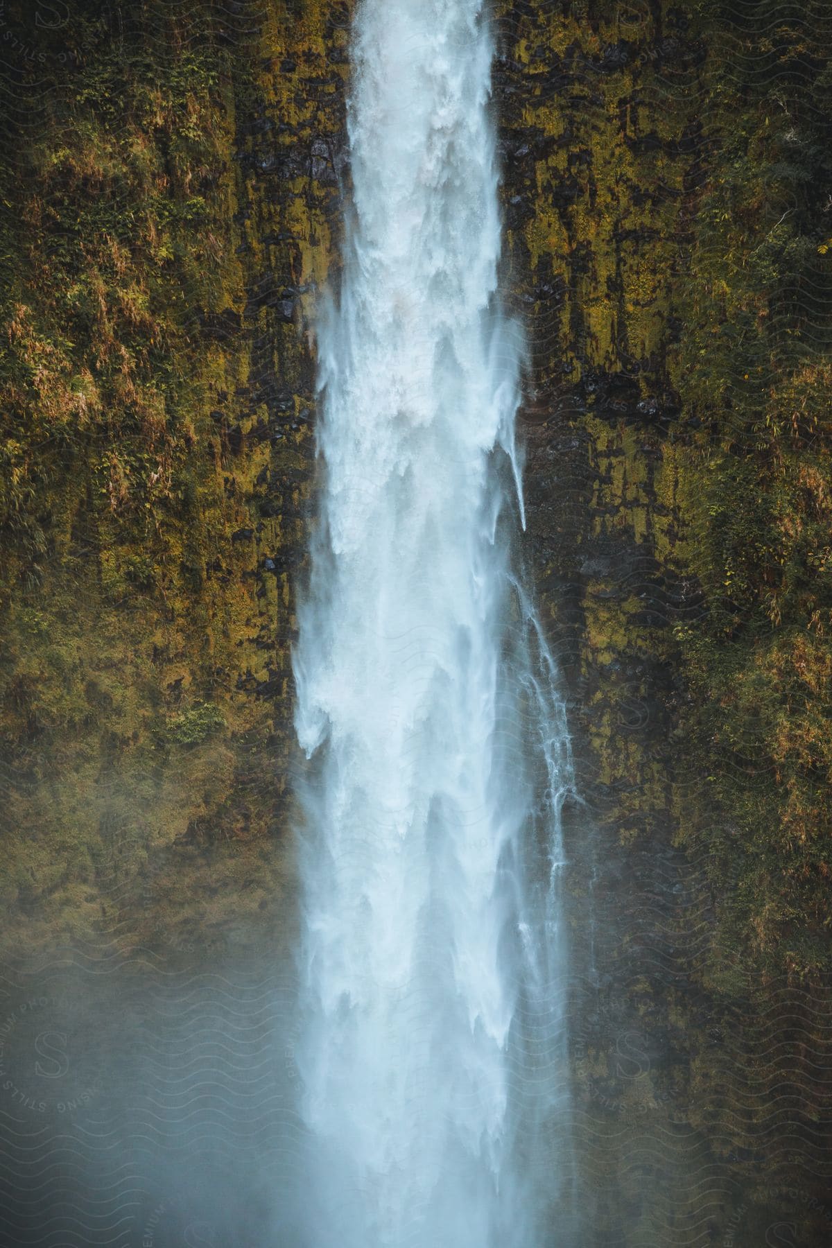 A large waterfall is flowing over a tall rocky wall.