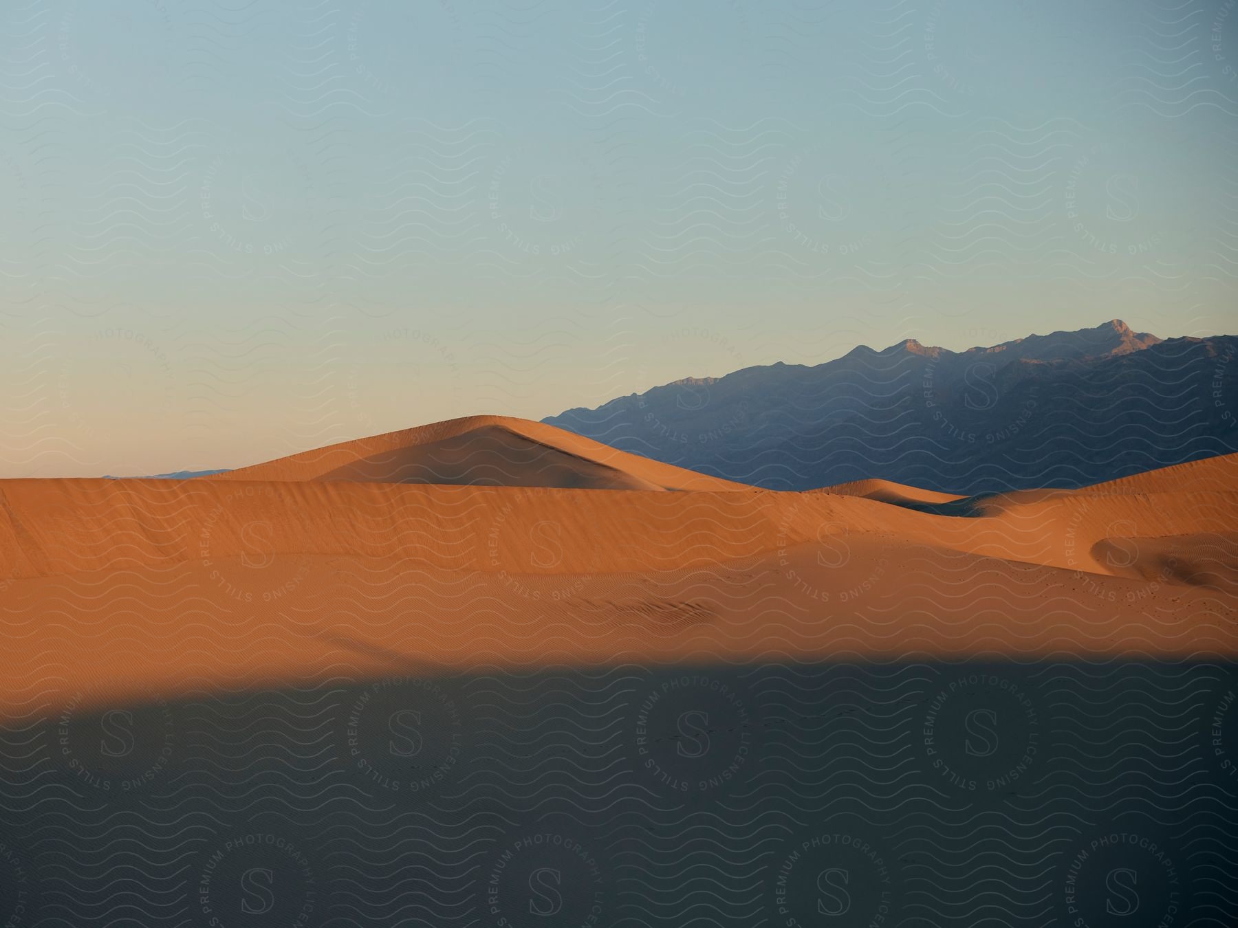 The sun is setting on the desert sand dune.