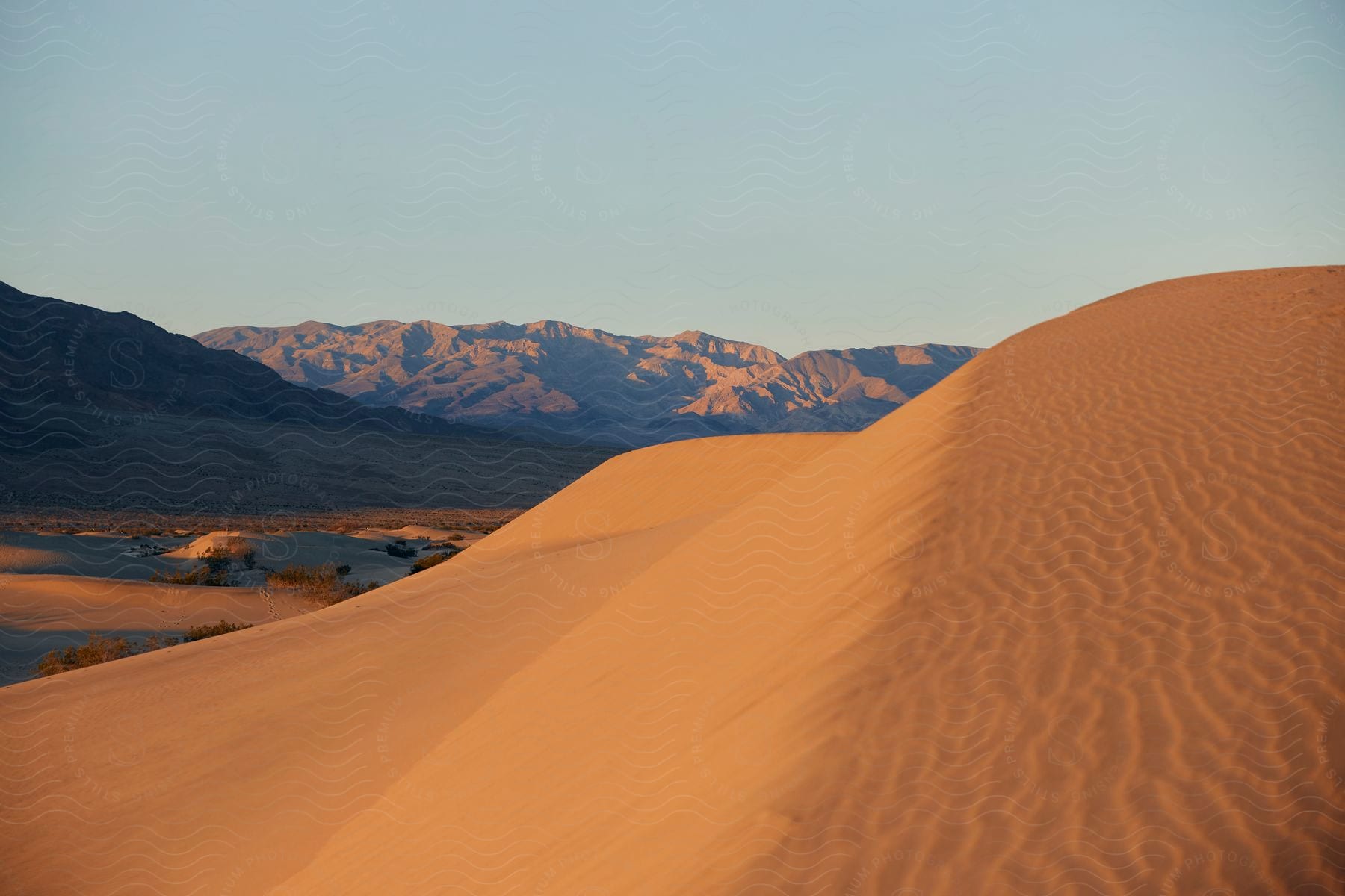 a sand dune forms below a mountain range