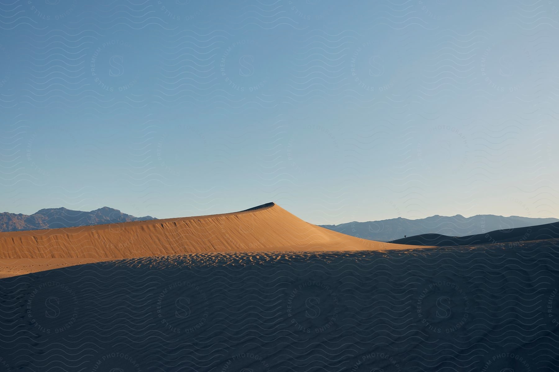 a sand dune casts a shadow on the desert below