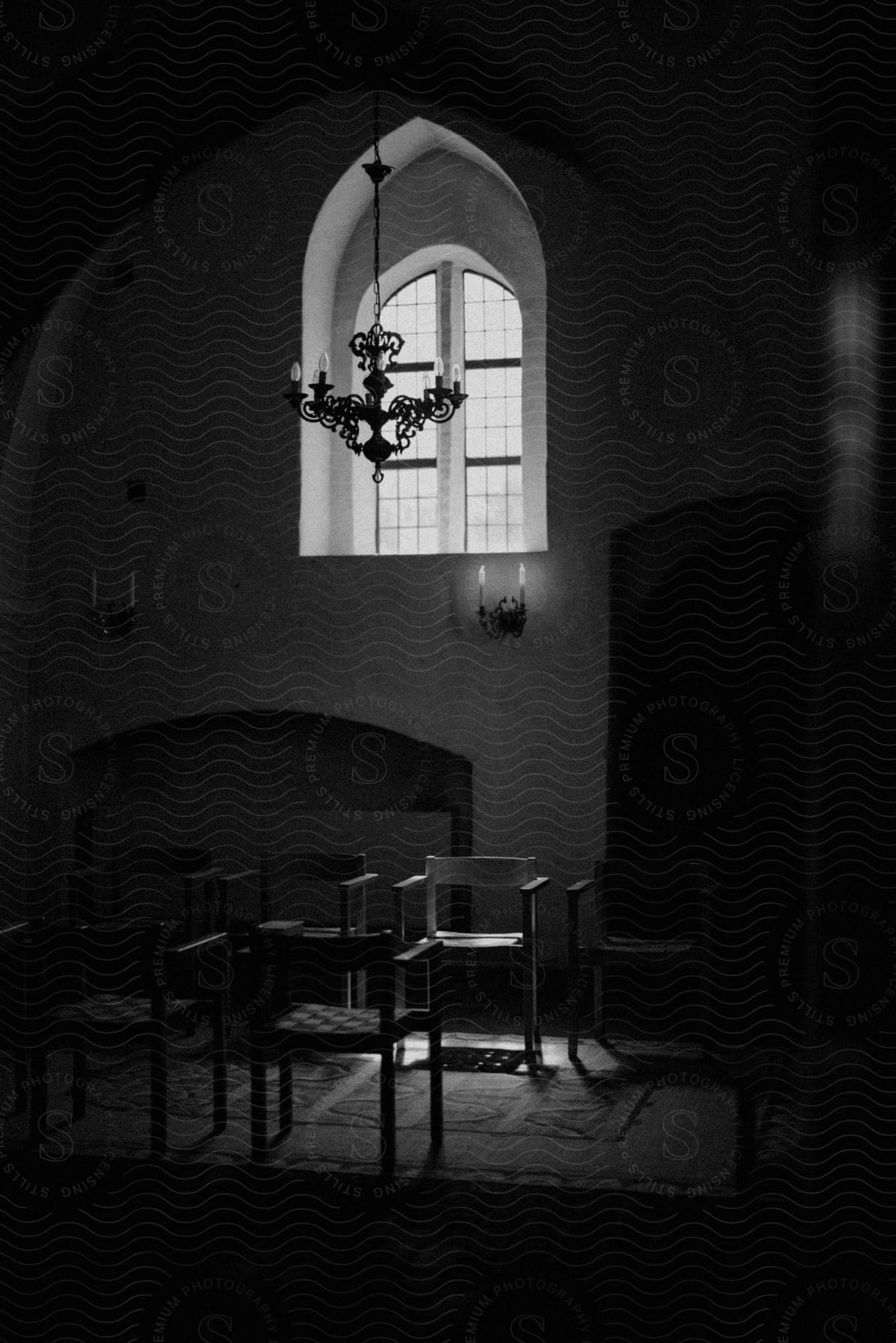 An old building inside with chairs placed in uniform on a carpet inn black and white.