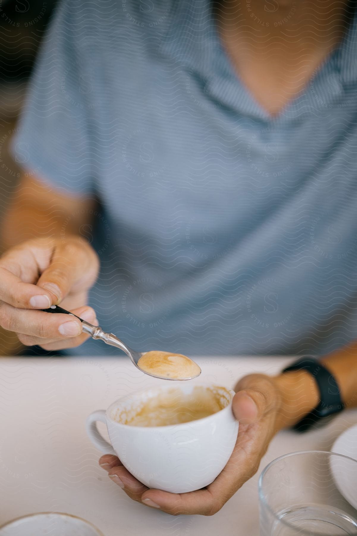 A person holding a coffee mug and a spoon with coffee.