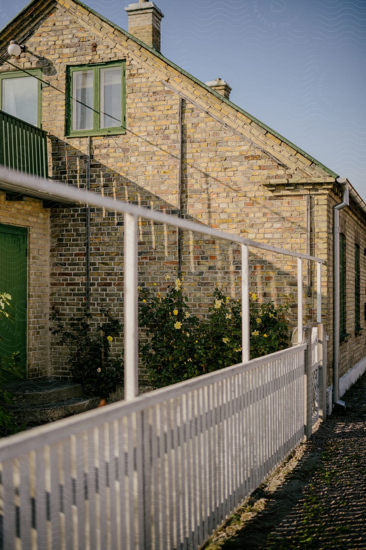 An old brick farmhouse with yellow flowers growing near the back door.