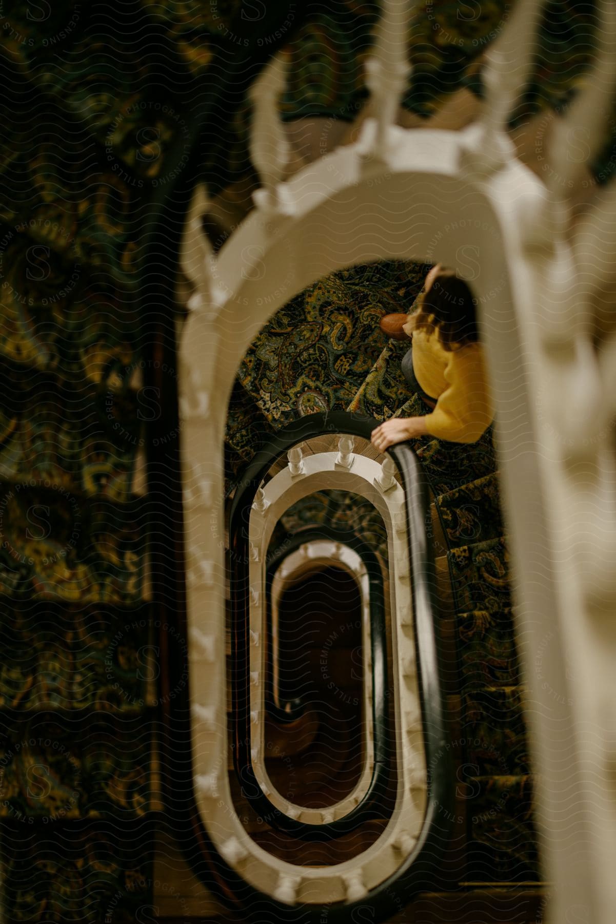 A spiral staircase with a person dressed in yellow descending.