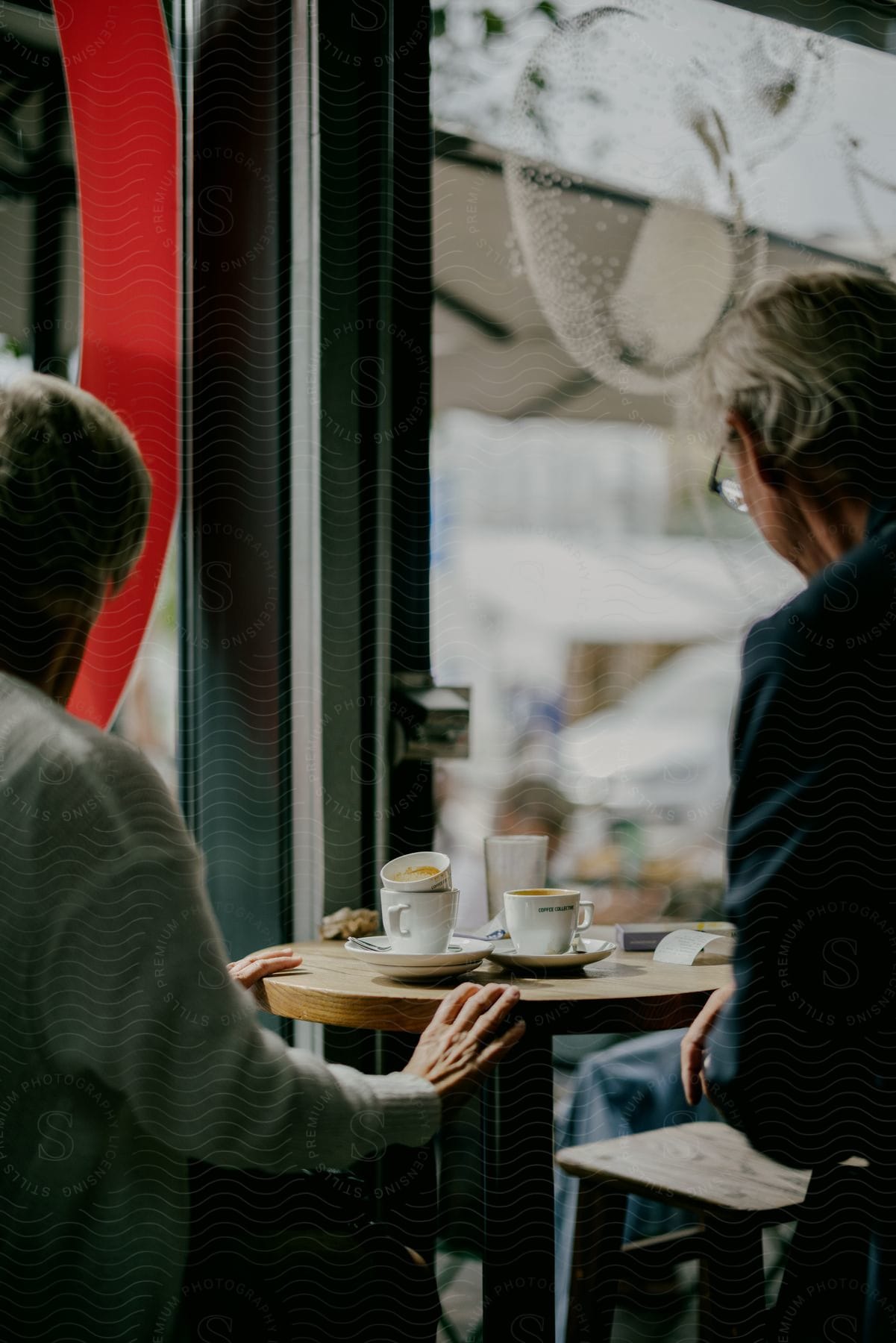 An elderly couple enjoys a cup of coffee and each other's company in a cozy coffee shop on a fall day.