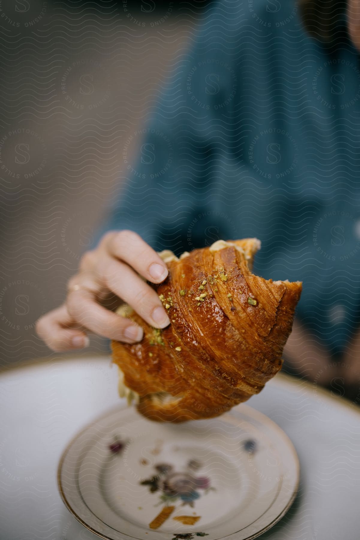 A women is sitting at a table eating a croissant.