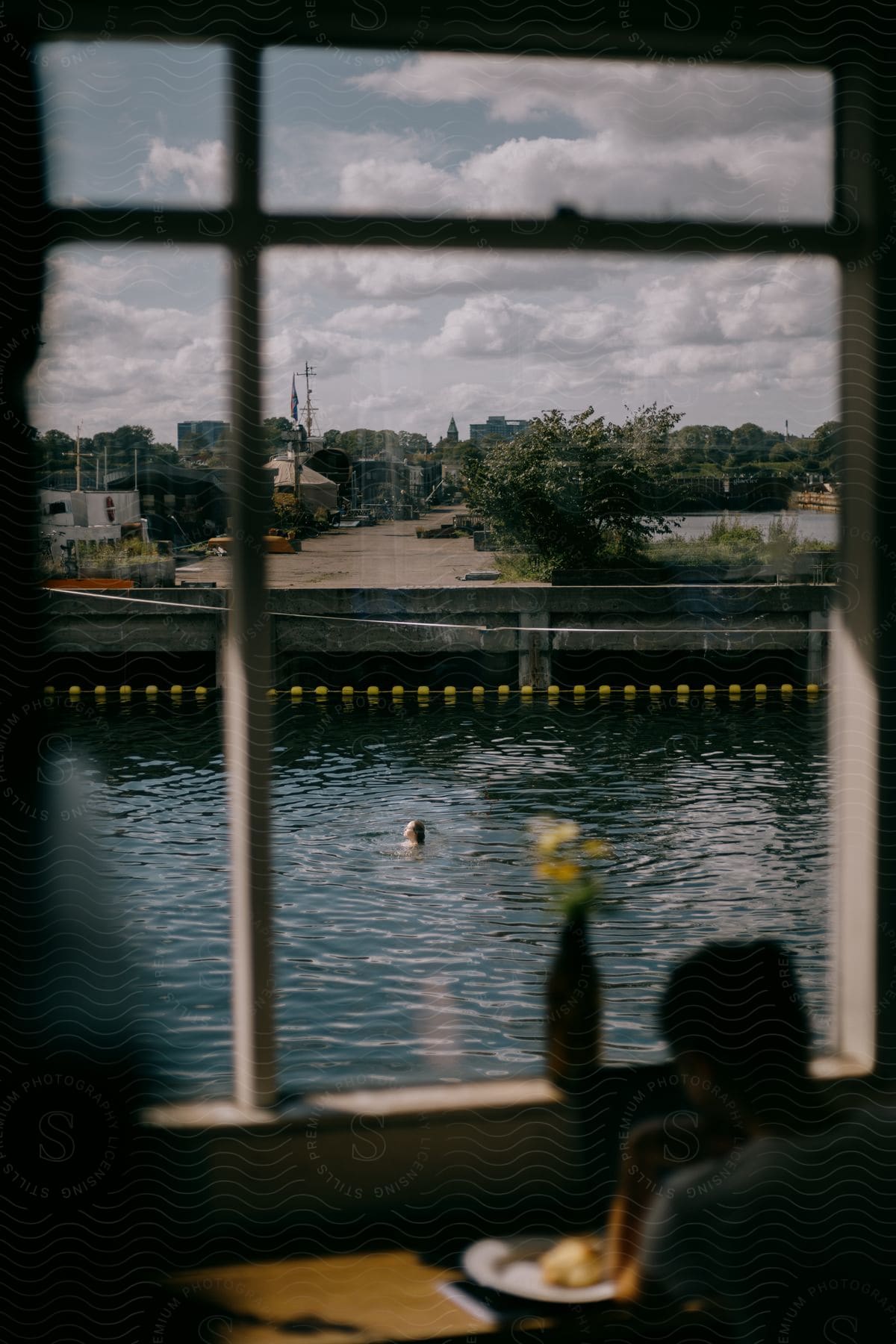 A view of a girl swimming through a building window.