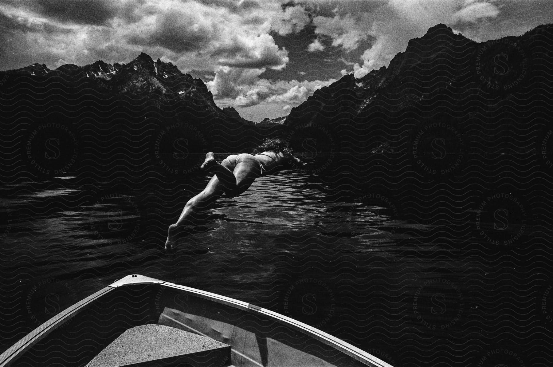 A woman diving off a small boat into a lake.