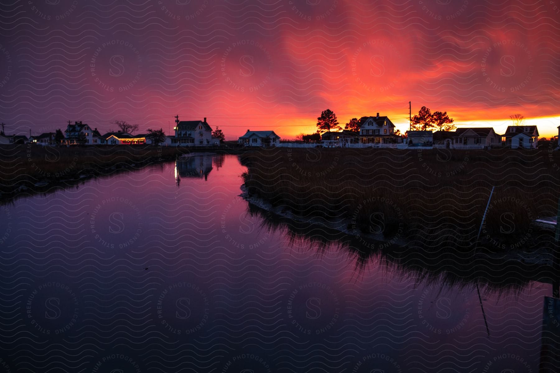 A country road with multiple houses with the sunsetting behind them.