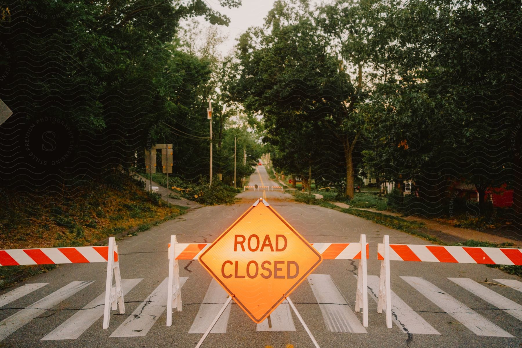 Traffic barriers and a road closed sign across a neighborhood street