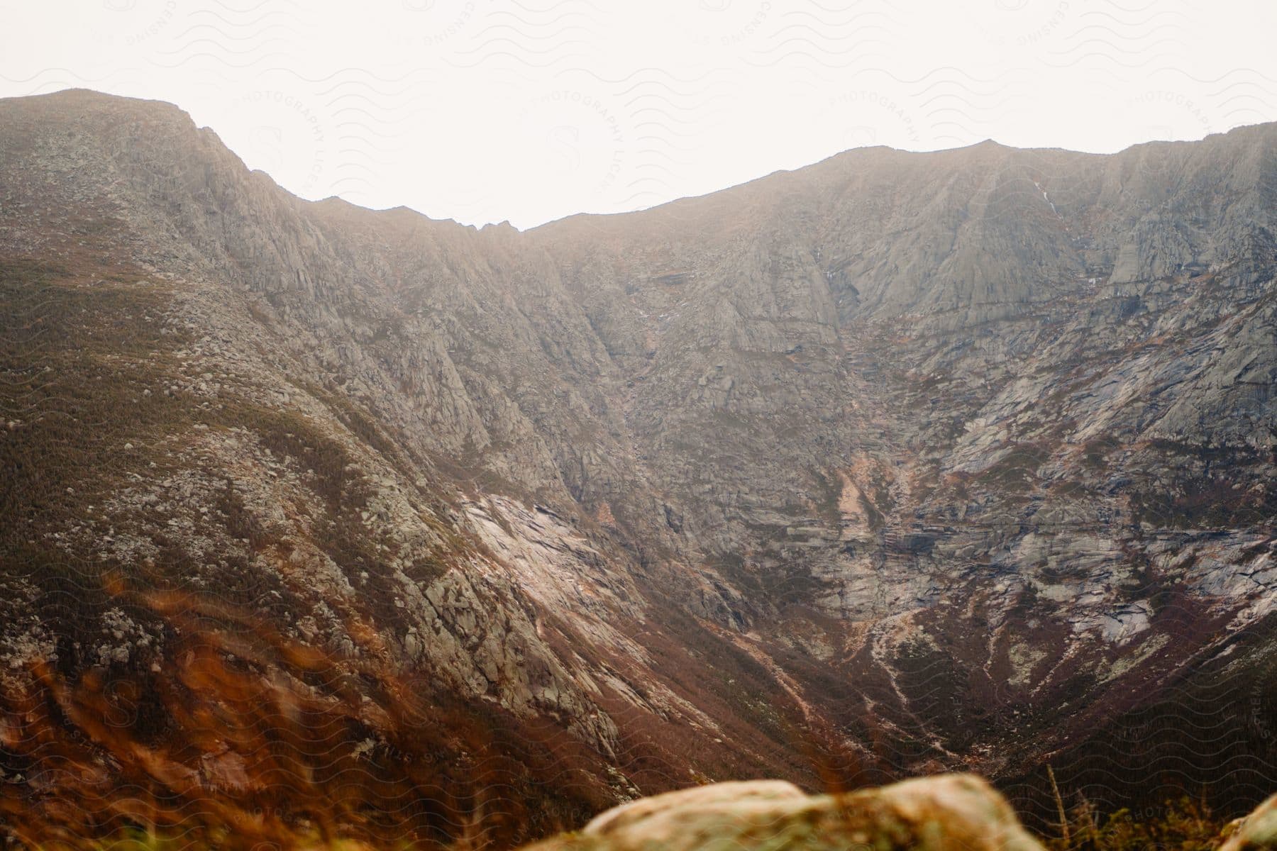 A mountain with steep cliffs on it in the distance on a bright sunny day.