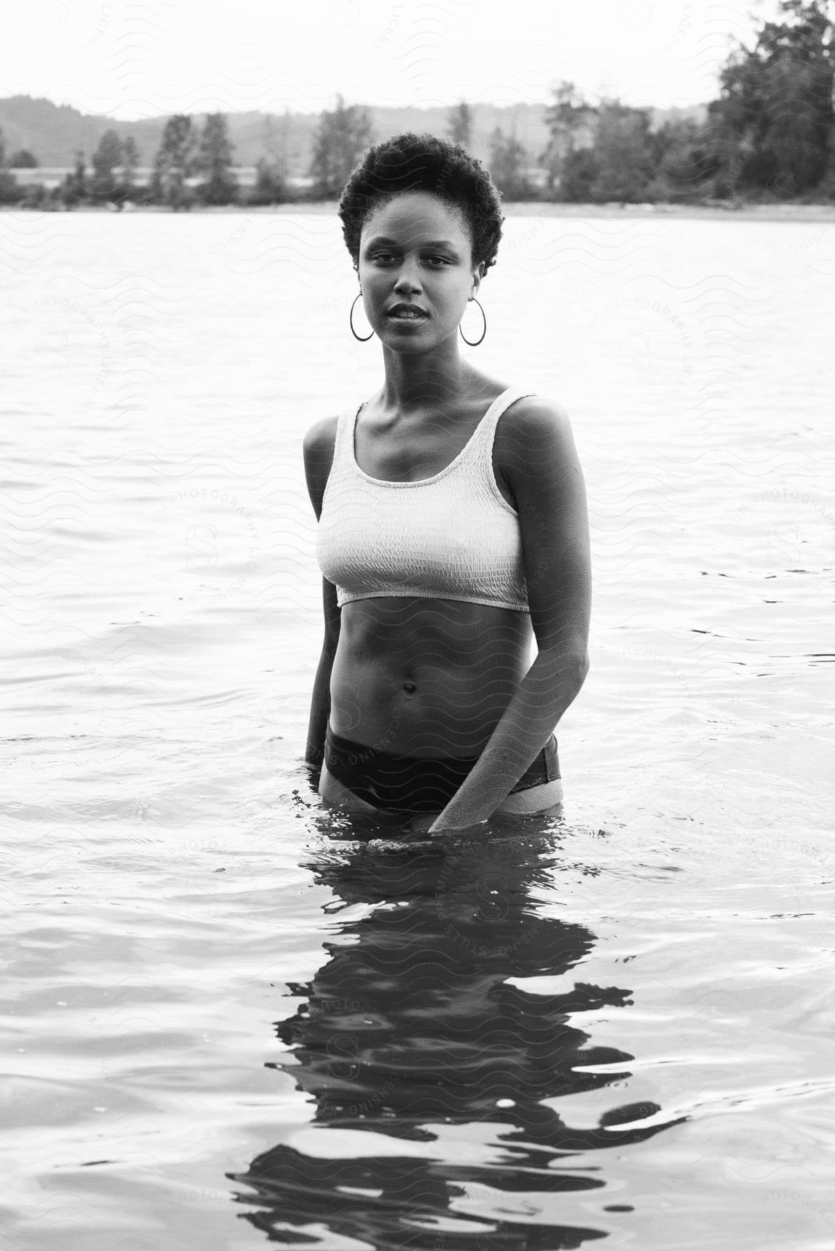 A woman standing in water up to her waist modeling, with a neutral look on her face