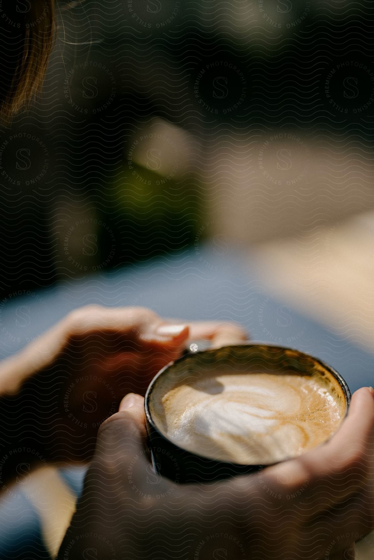 a person hands holding a cup of coffee in a black coffee mug