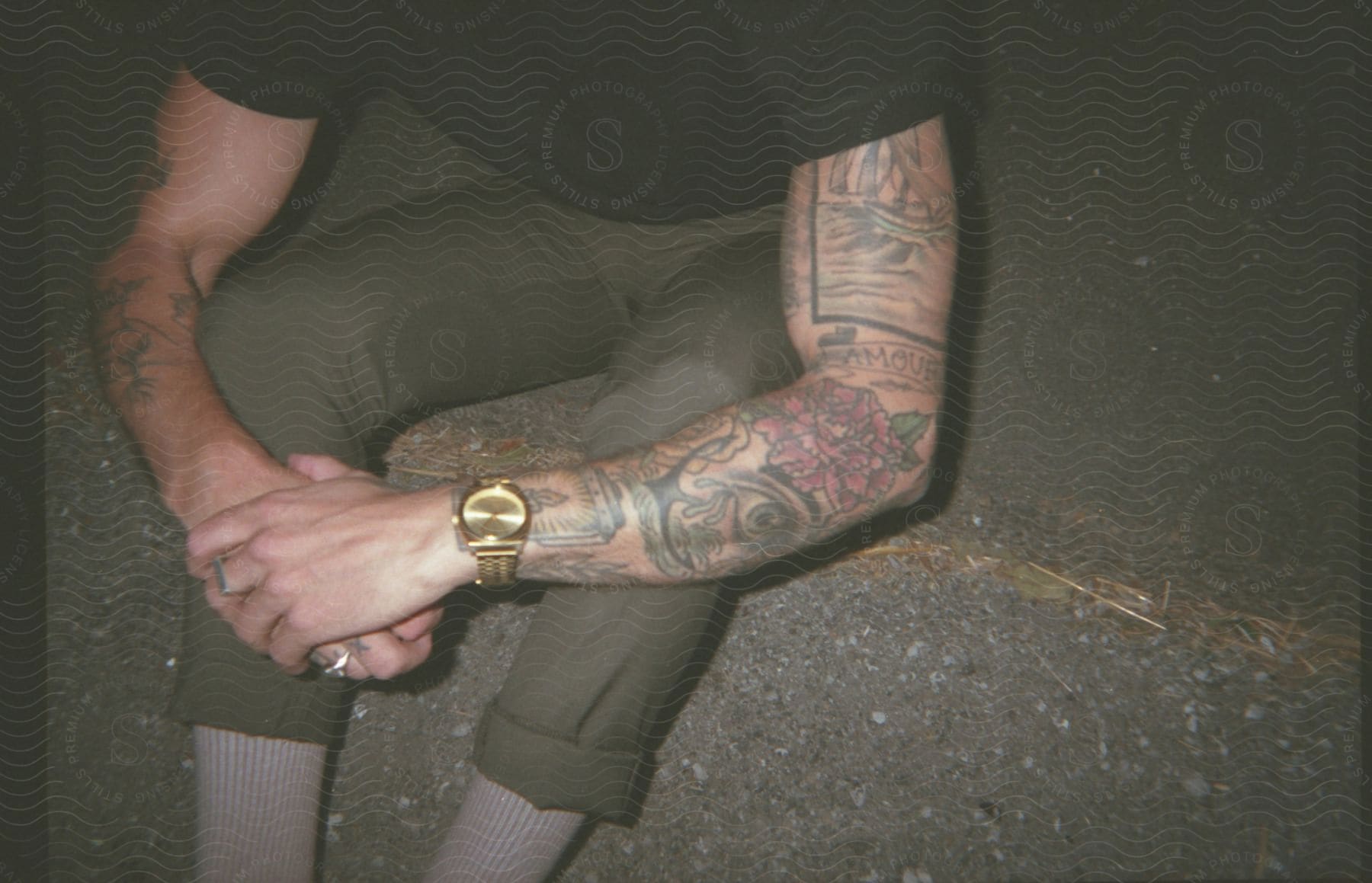 Man sitting wearing casual clothing and a golden wristwatch.