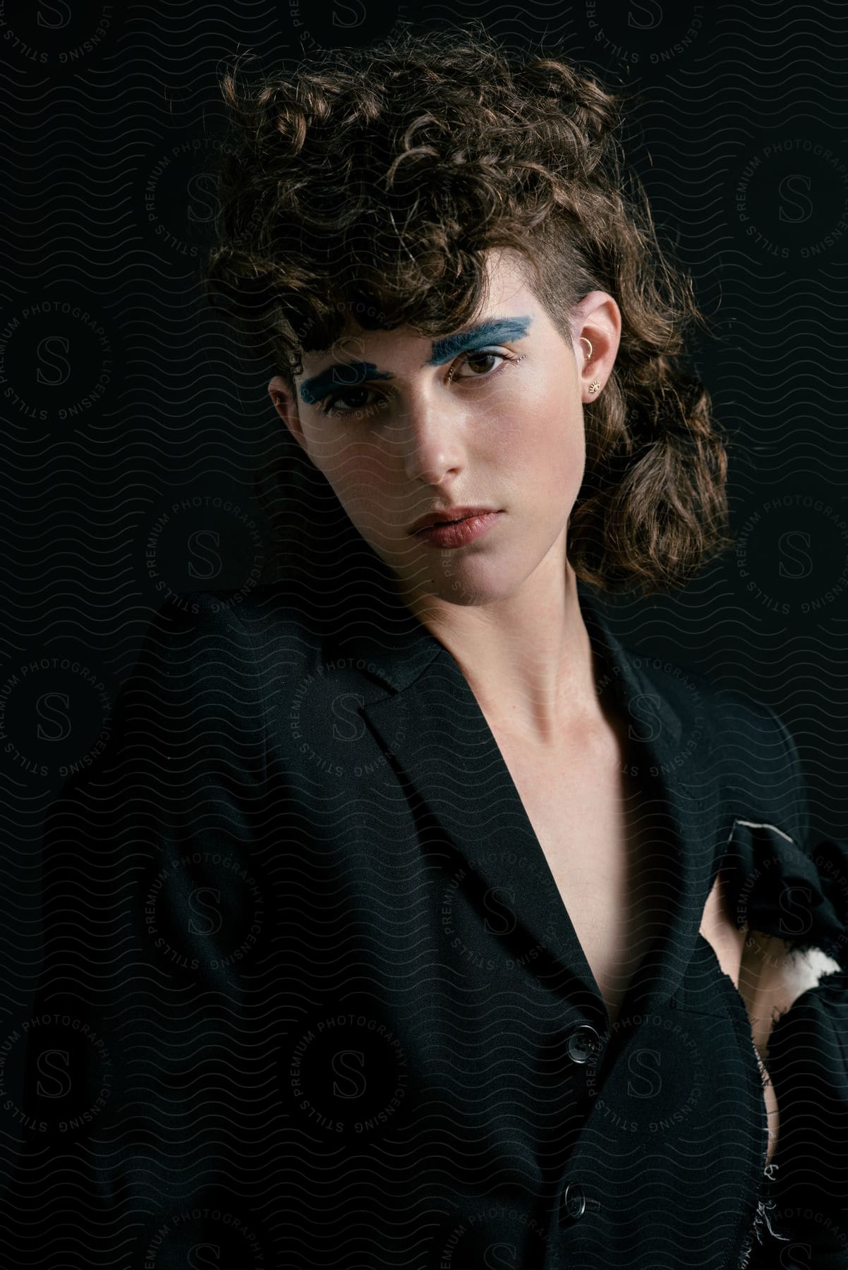 A woman with eyebrow makeup and black clothing posing.