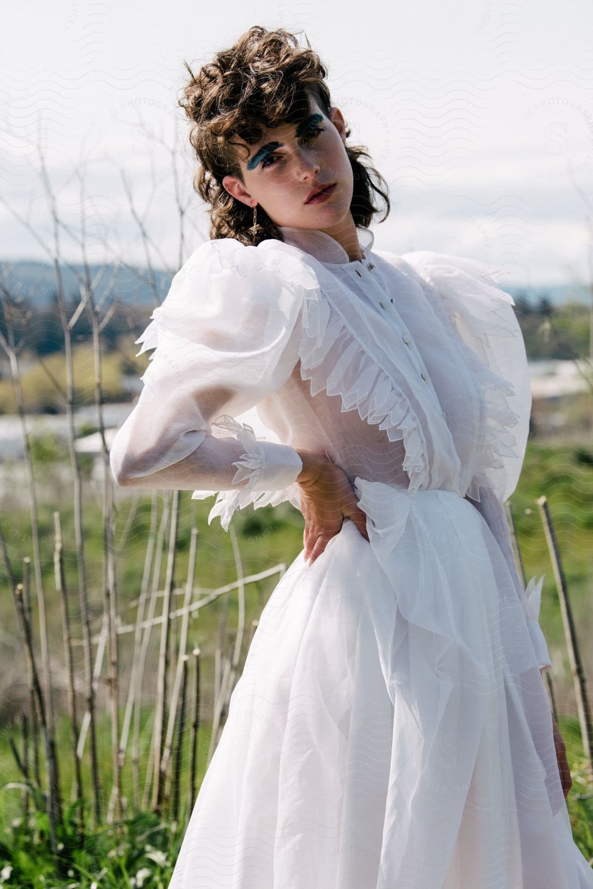 A woman models a white semi sheer dress outside in the bright sun