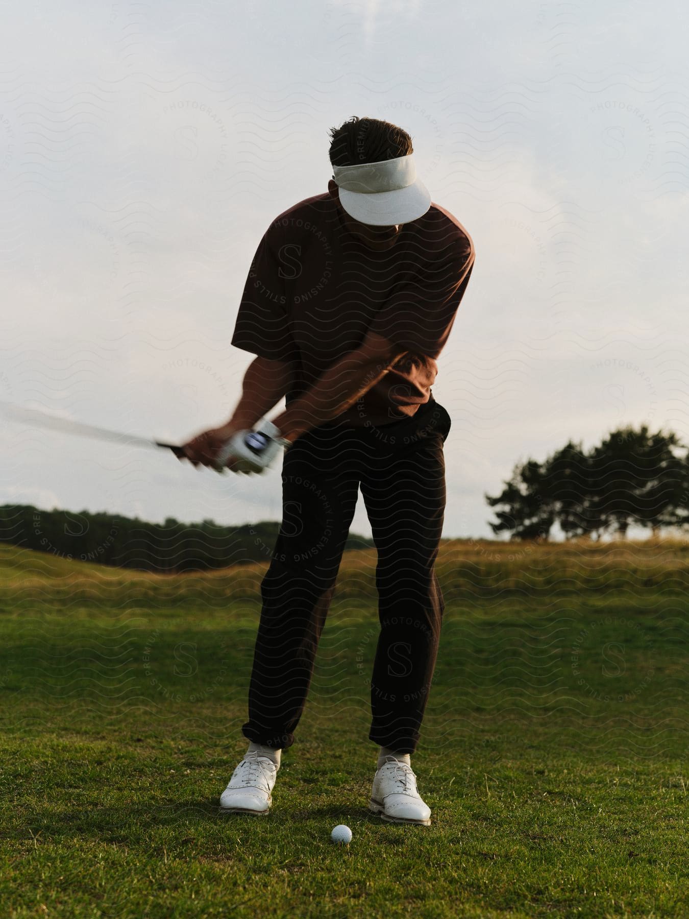 A man is playing golf with his club raised ready to strike the ball