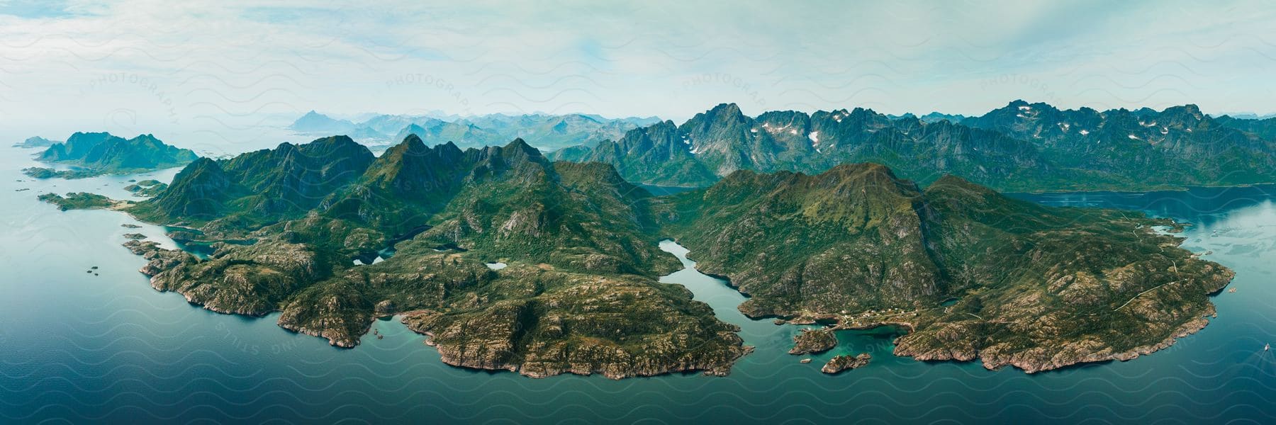 An aerial view of an island at the edge of the ocean with some clouds in the distance.