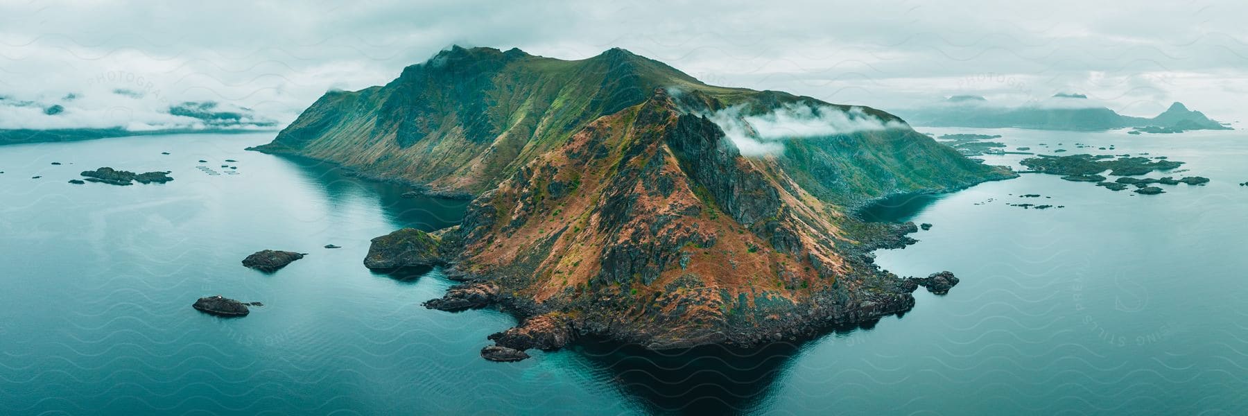 A Mountainous Promontory With Steep Cliffs Extends Into A Tranquil Ocean