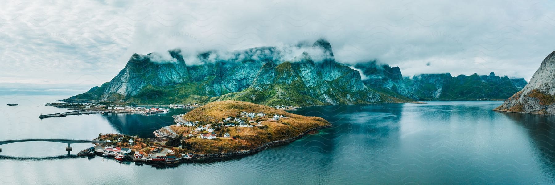 Panoramic view of a small coastal town on a promontory near the mountains by the sea.