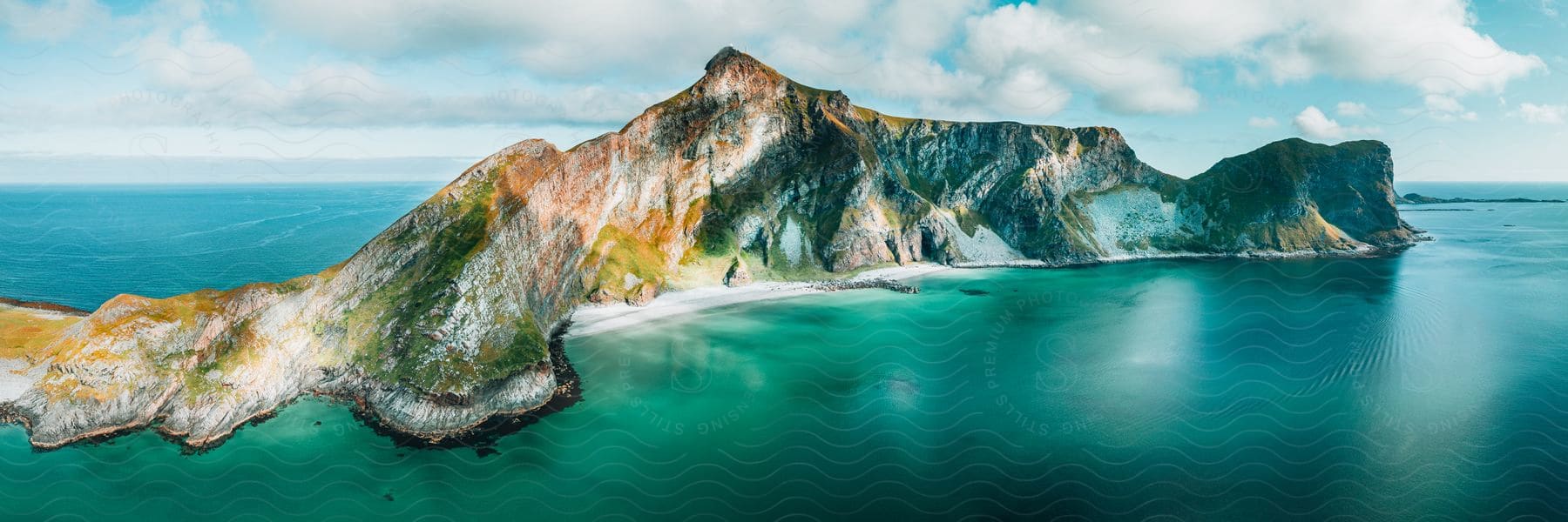 A rocky island with a tall peak and steep coastline on a cloudy day.