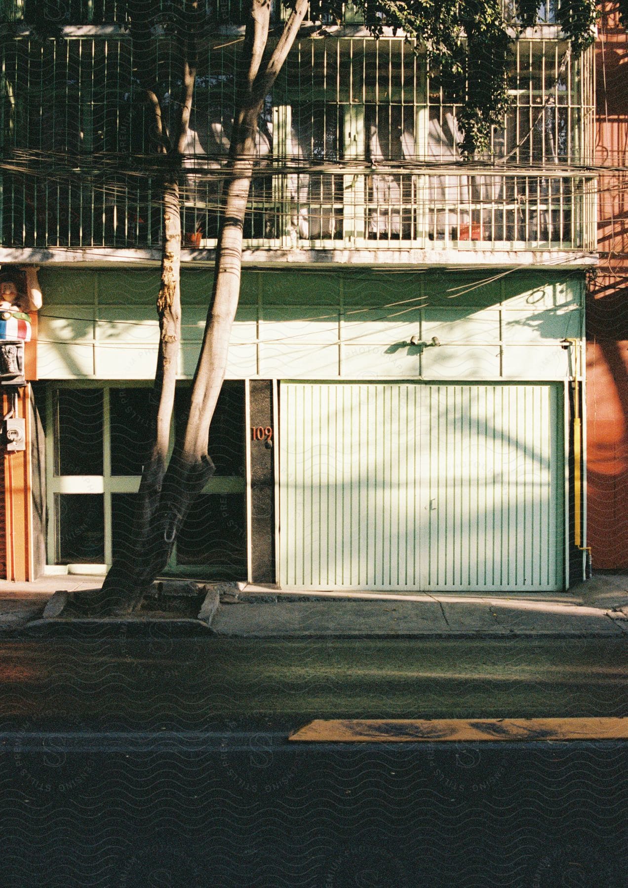 A building near the road with mint green siding and doors.