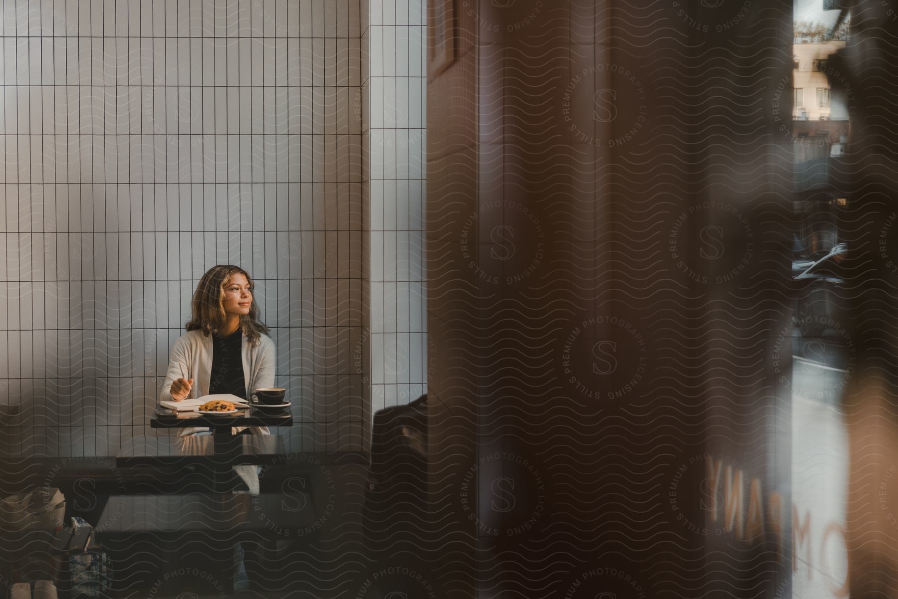 Woman looks out window while sitting at table with food in restaurant.