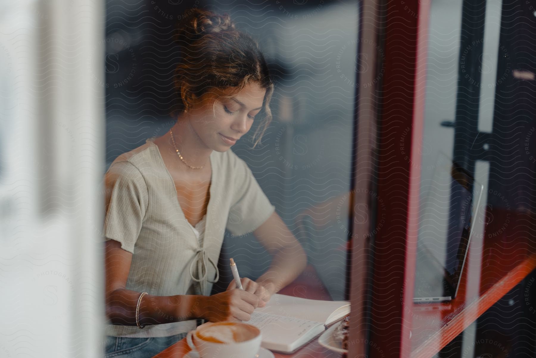 A woman sitting in a restaurant while writing on a piece of paper.