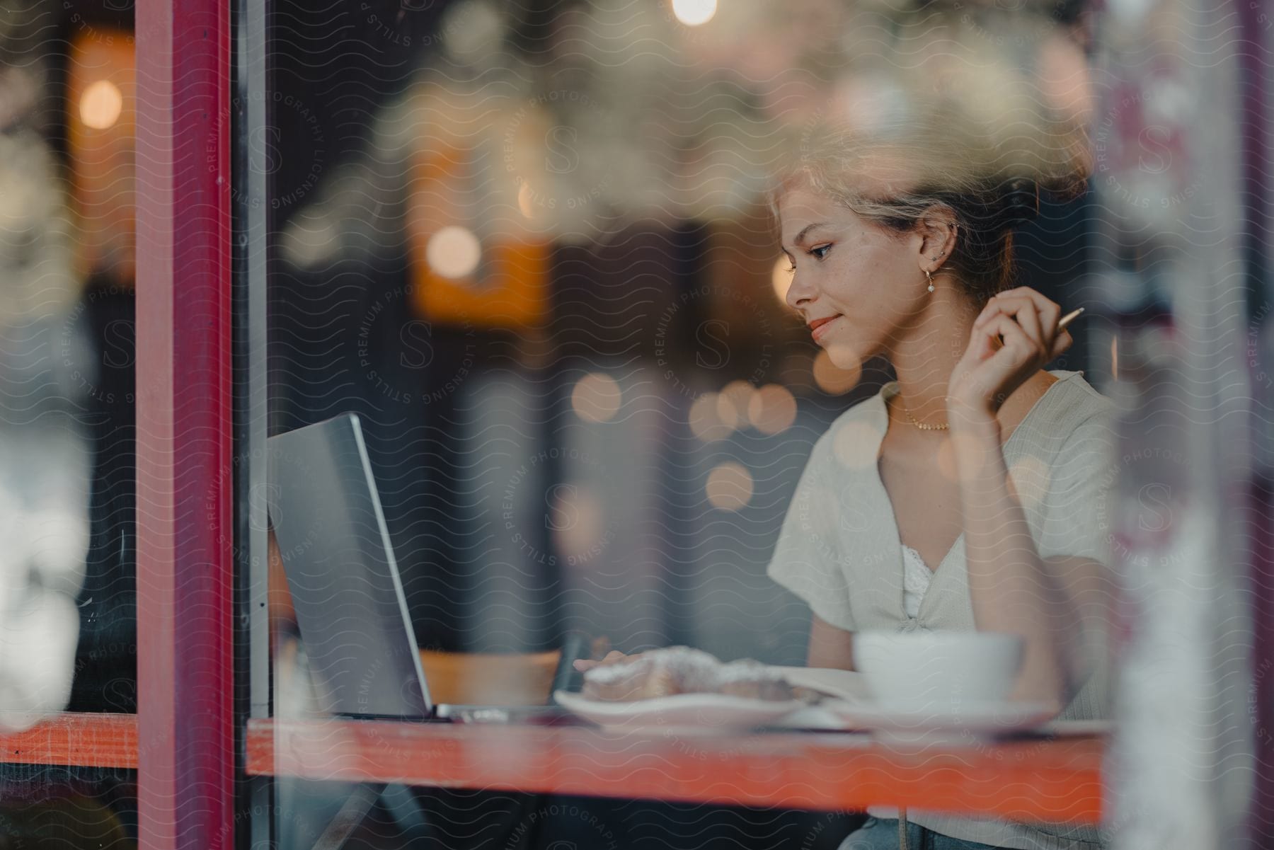 A woman sitting in a restaurant while using a laptop.