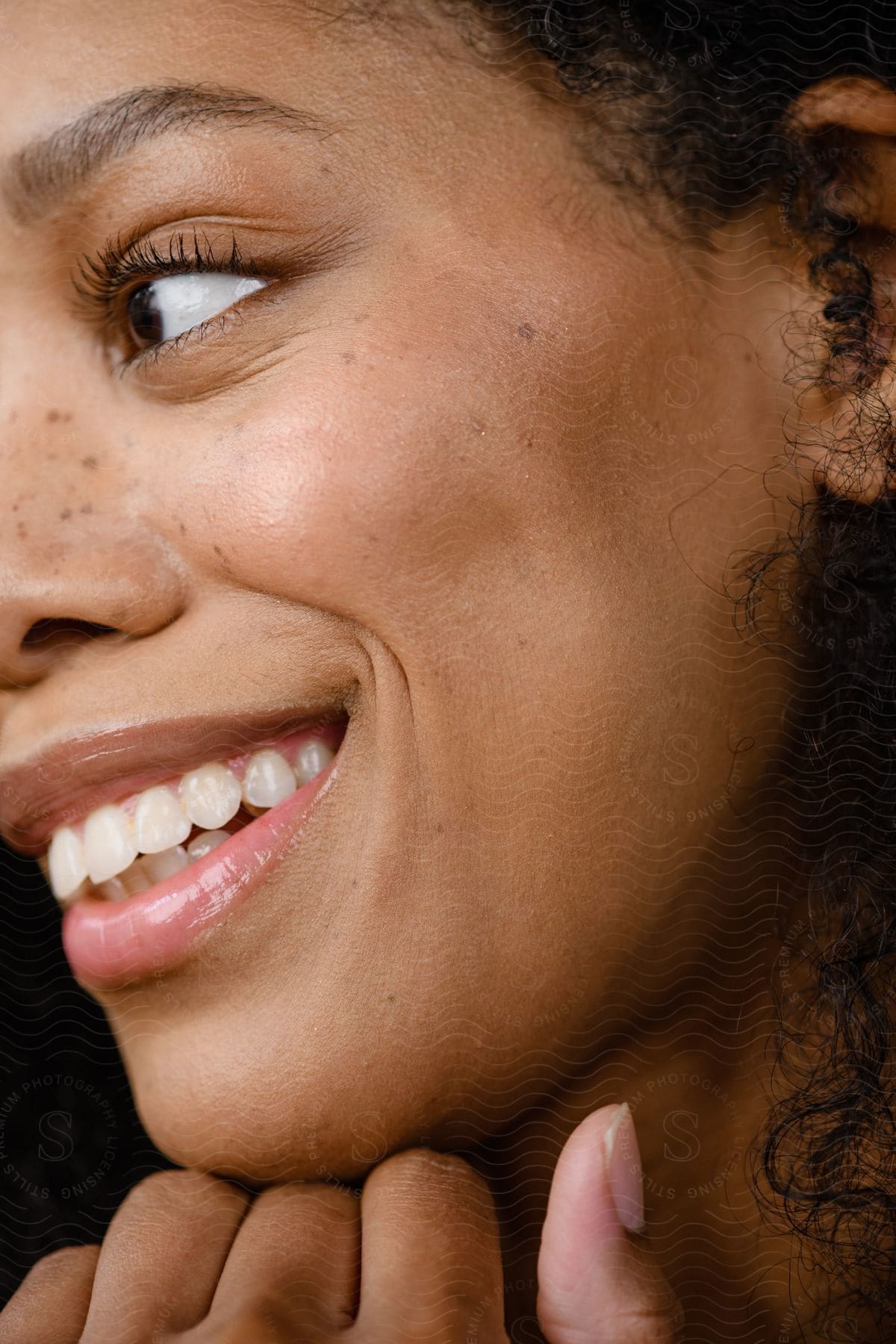 A woman gives a big smile as she looks to the left and the camera focuses on her face.