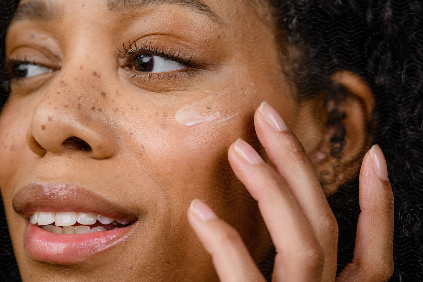 Woman applies lotion onto her face.