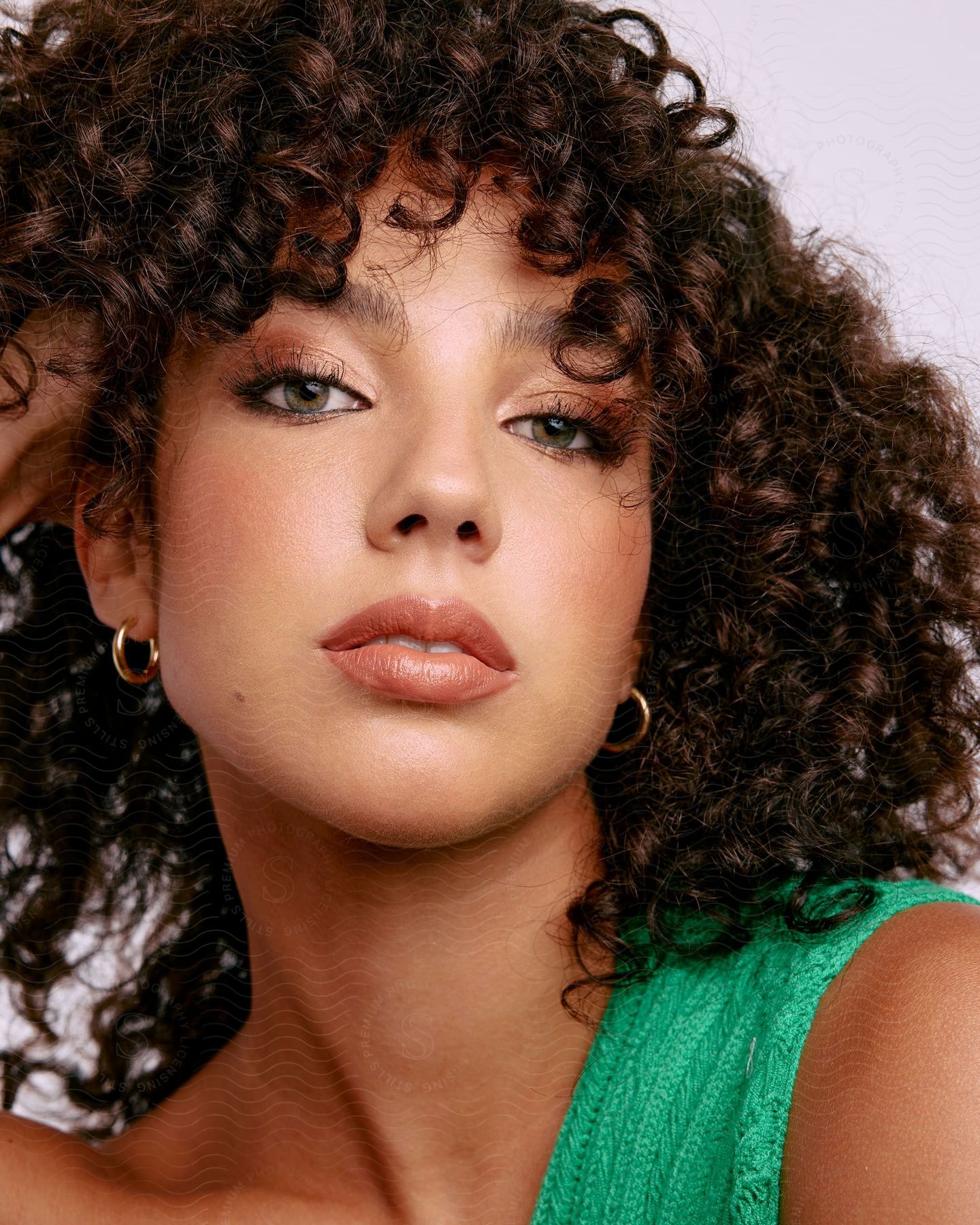 a model poses with her hand in her curly hair