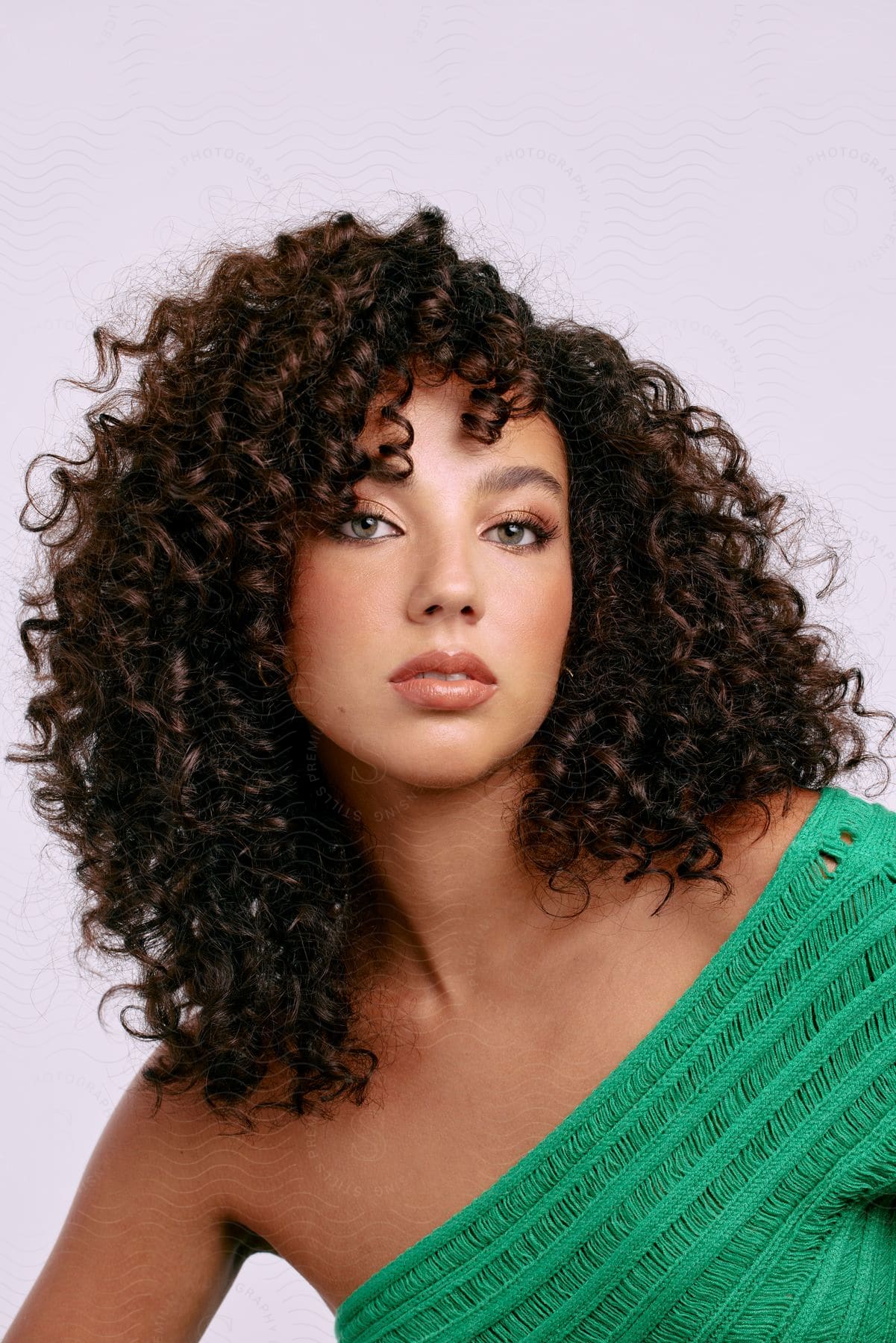 A young woman poses for a portrait in a green, off-the-shoulder blouse.