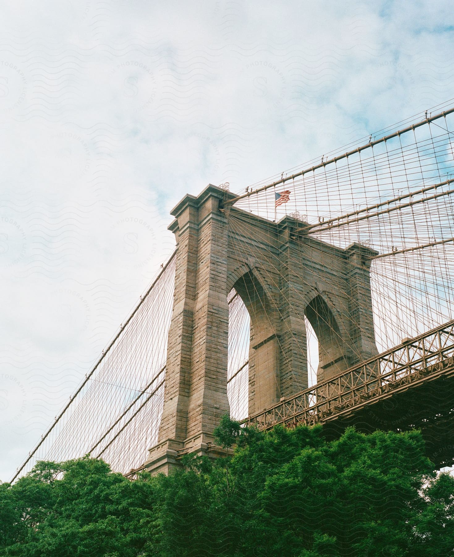 arch on the brooklyn bridge in new york city next to trees during day time