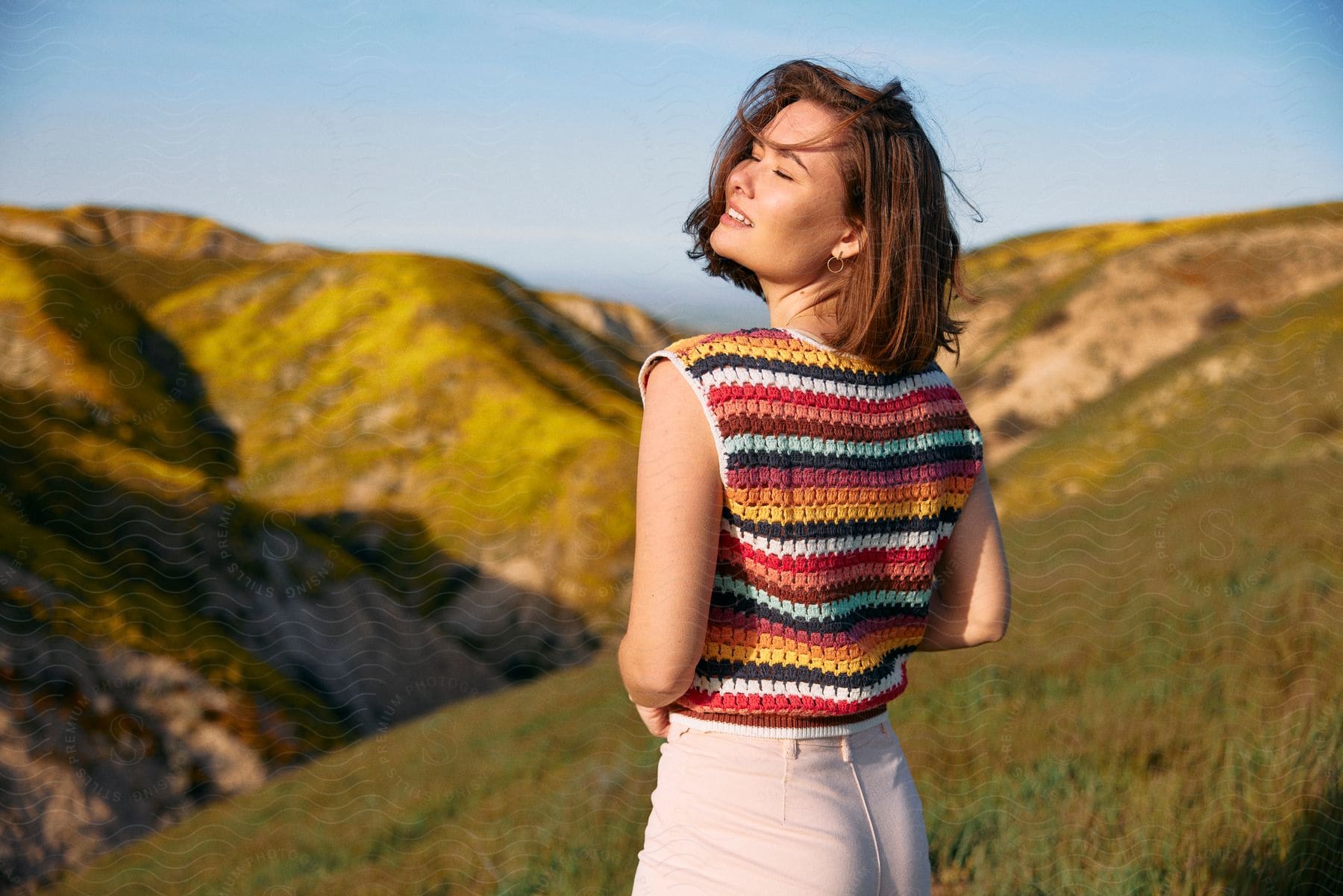 Sun shines on a teenage girl as she turns her head with mountains in the distance