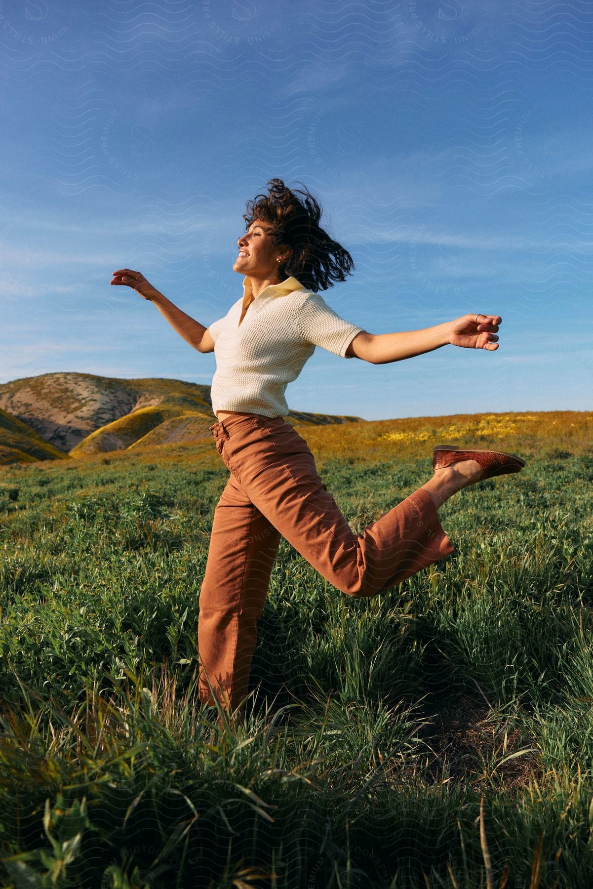 A woman having fun out in a field jumping around.