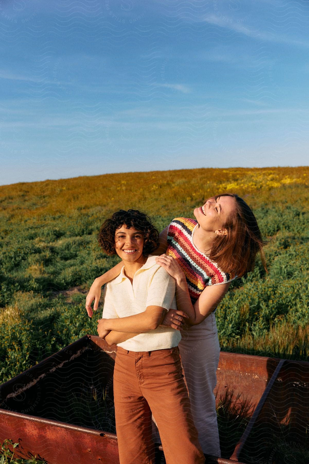 Two young teenagers stand in an area covered with short grass, sharing laughter