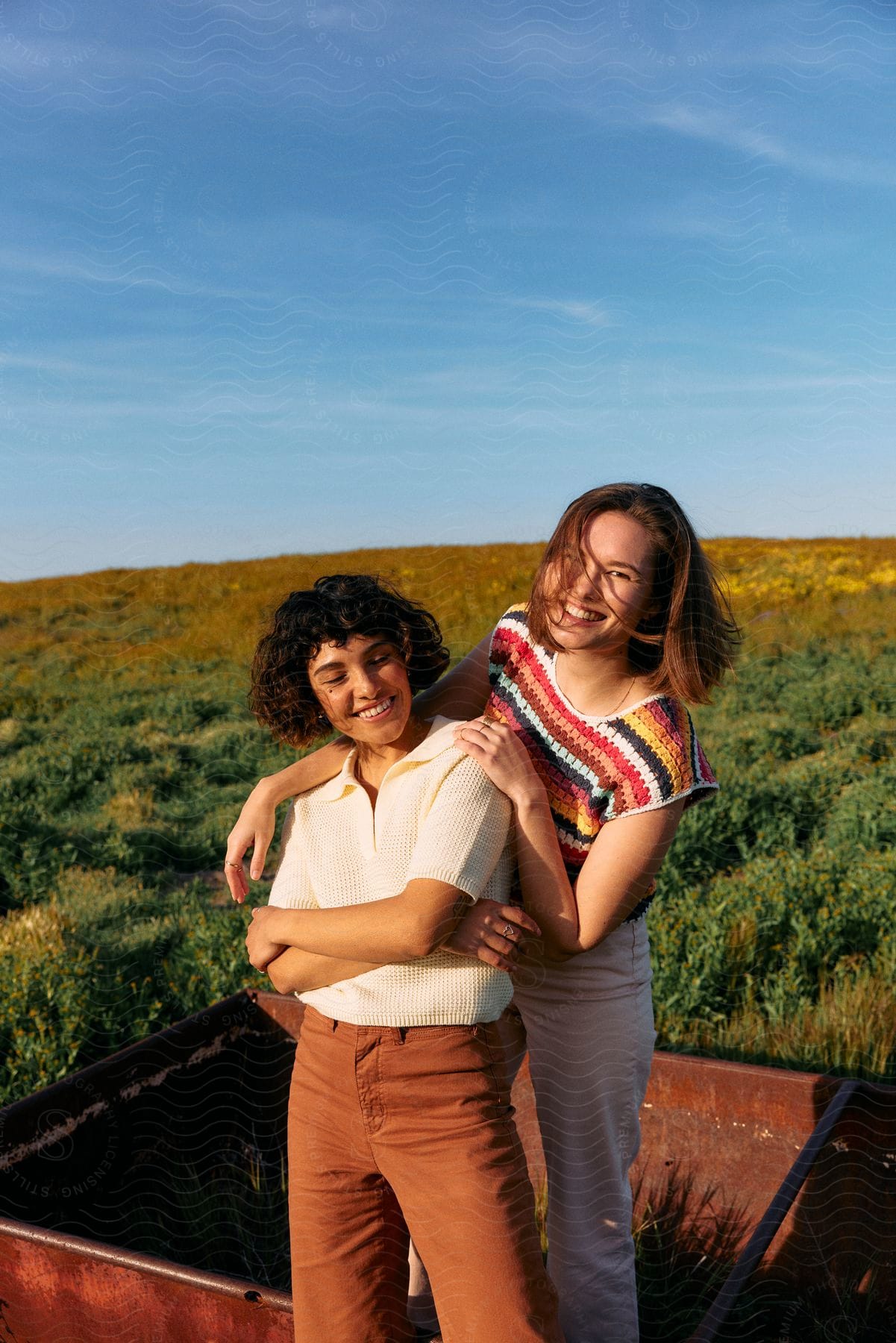 A teenage girl is standing in a metal bin smiling with her arms around a woman's shoulders