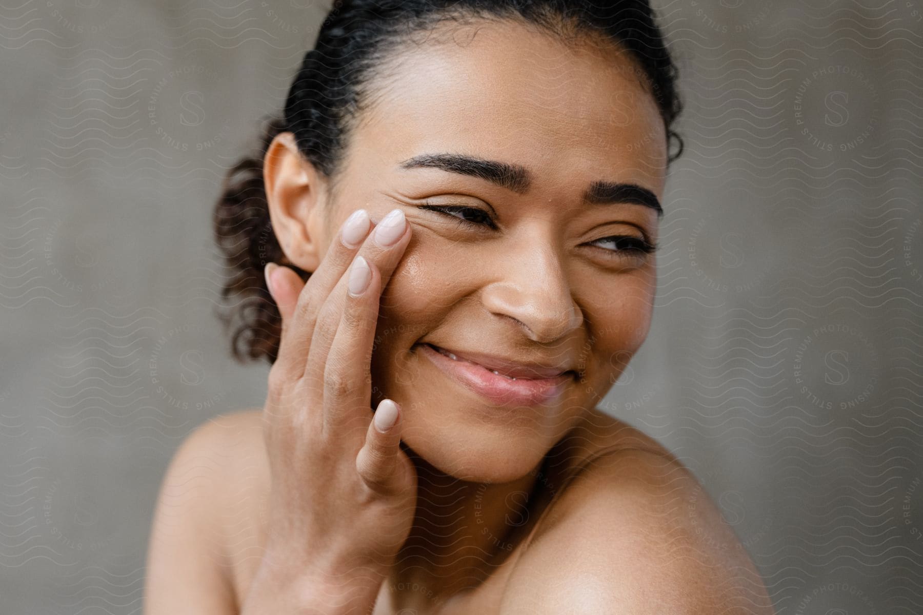 a woman smiles while touching her cheek