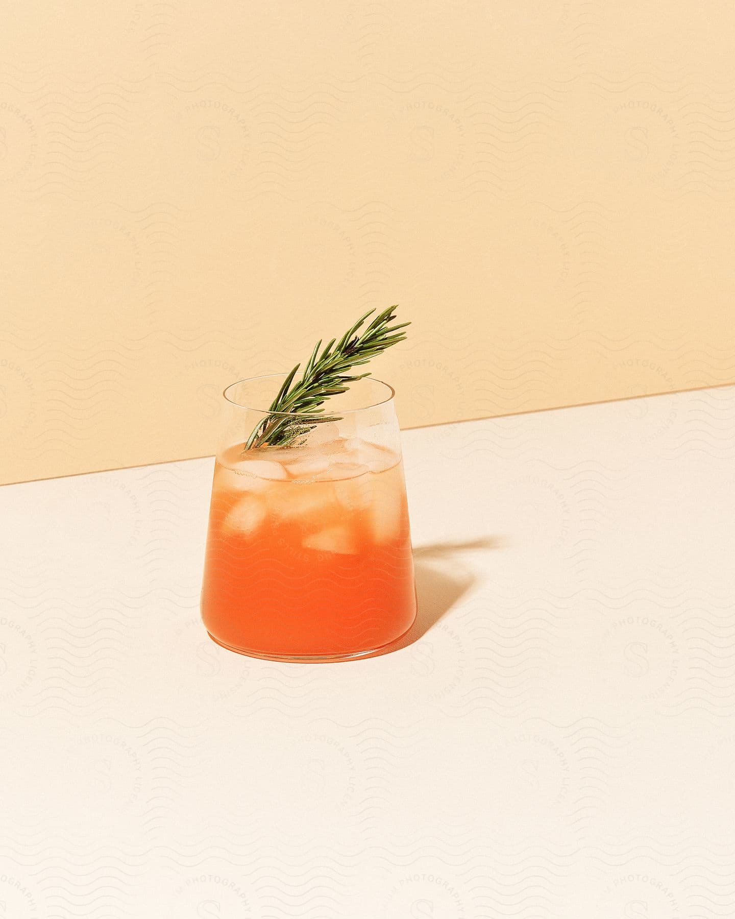 An alcoholic beverage in a glass cup with a pine needle clipping.