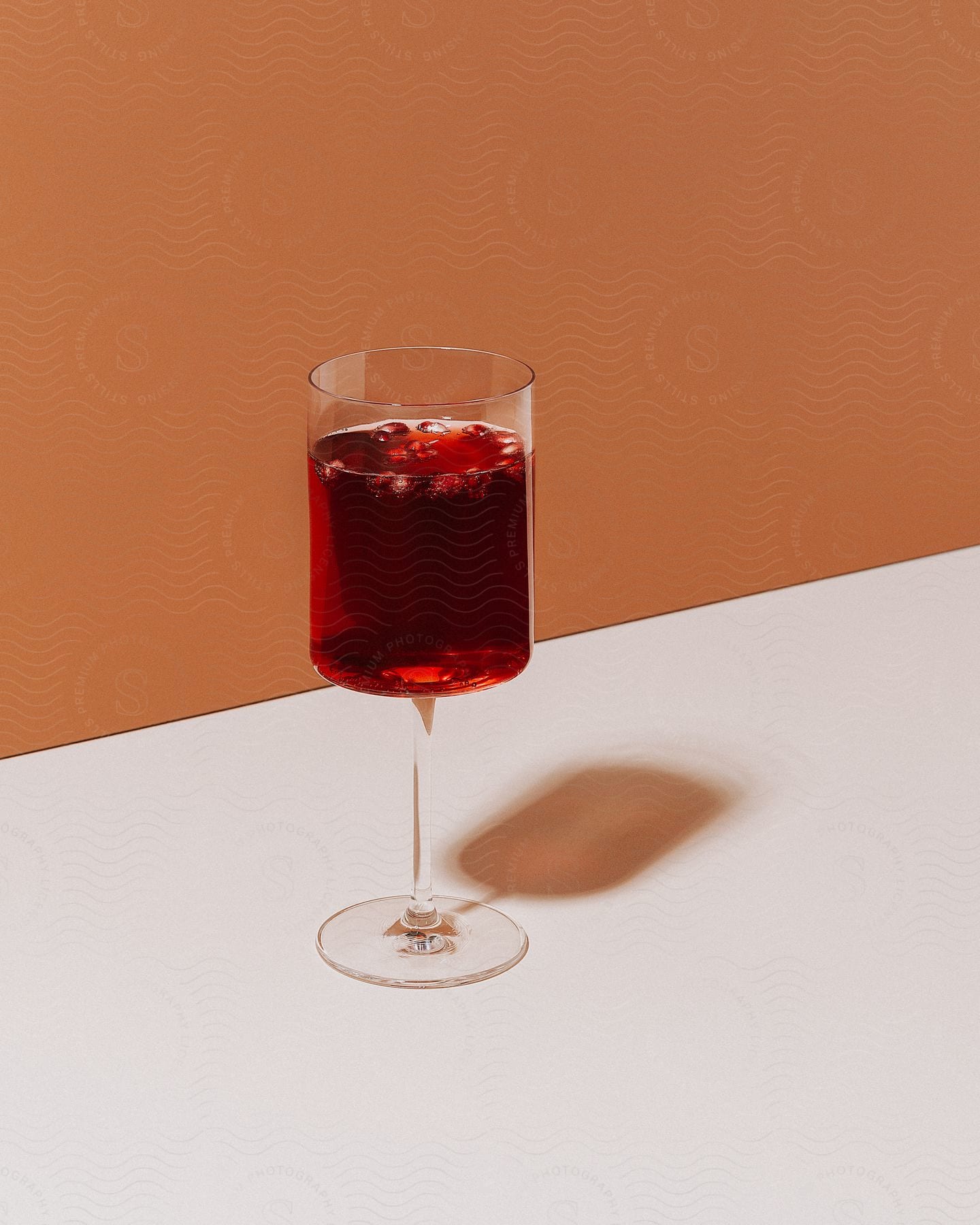 A red drink is in a glass on a table near a wall