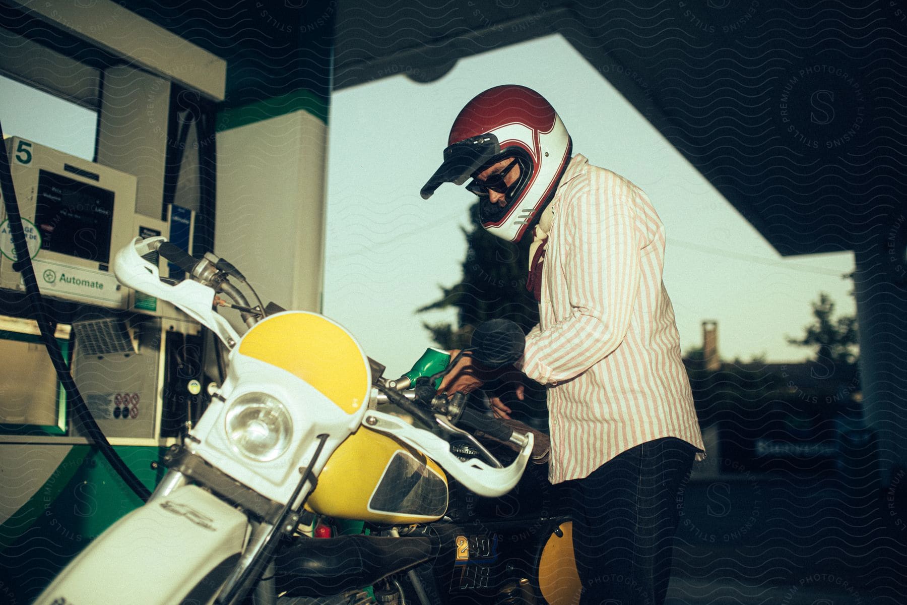 A man puts gas in his motorcycle at a gas station