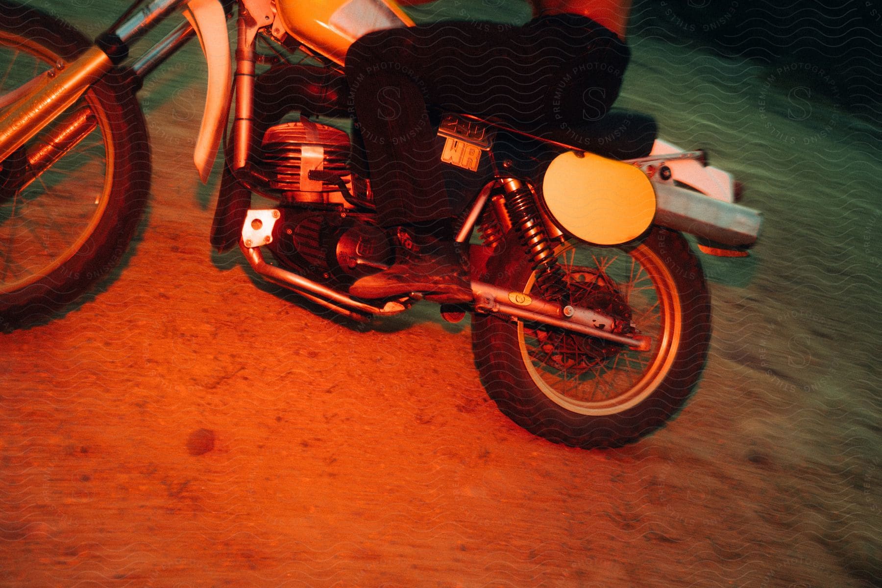 Person on top of a motocross bike with reflections of red lights.