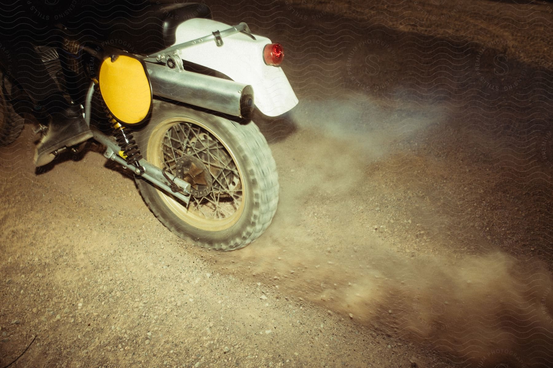 A dirt bike wheel kicking up gravel.