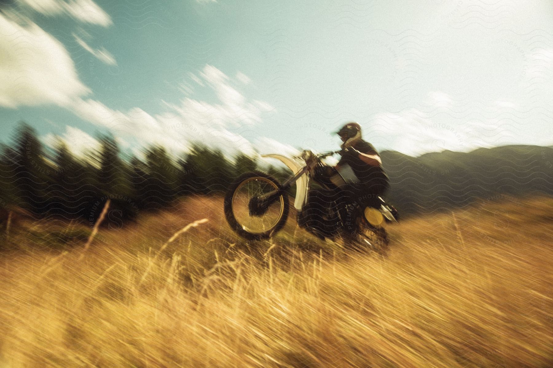 A person doing a wheelie on a dirt bike out in a field.