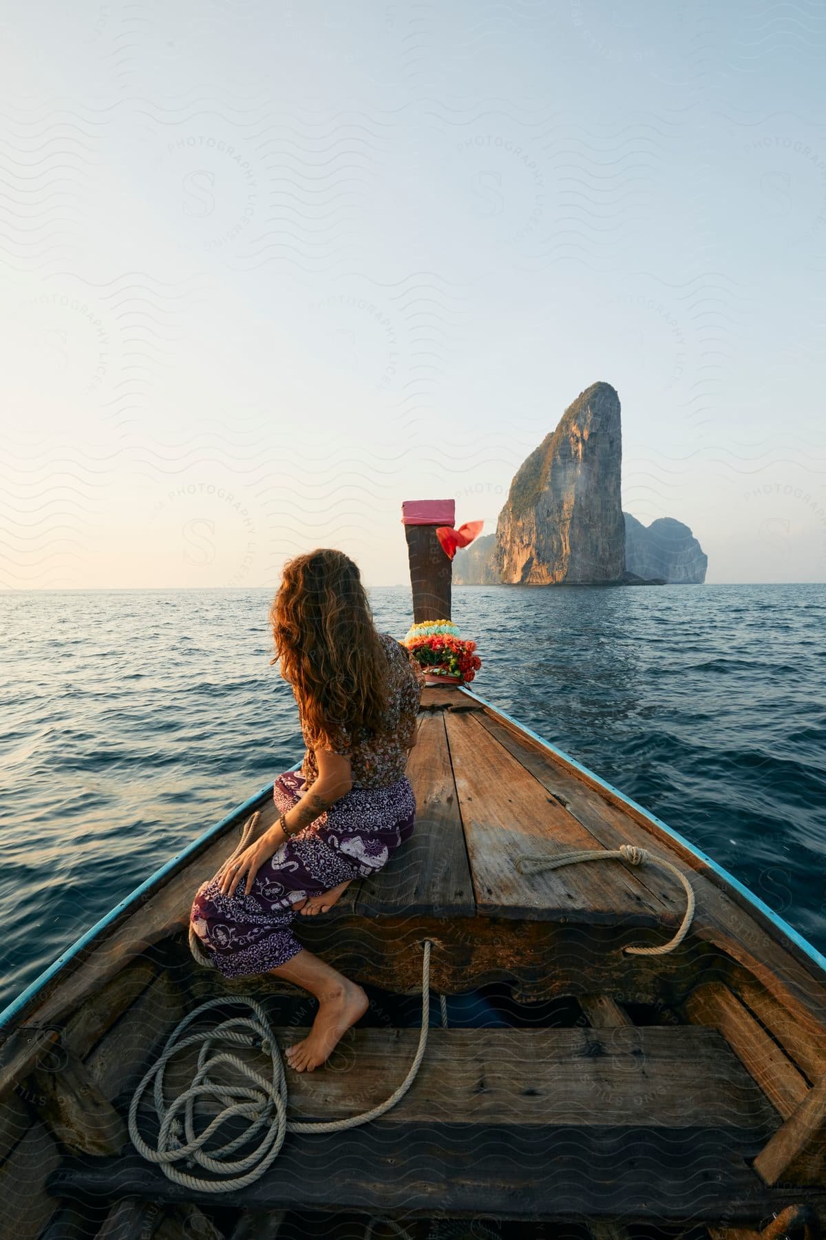 Woman Sits In Boat Heading Toward Small Island