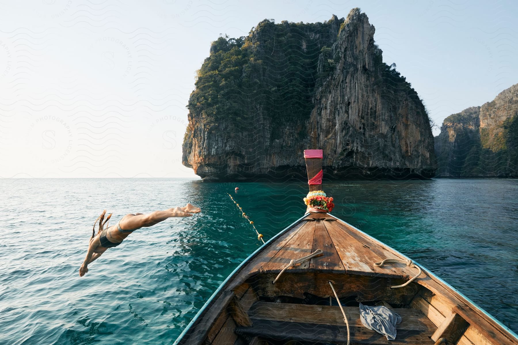 Female Jumping Out Of A Boat On The Water Near To A Promontory Outdoors During Day Time